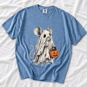 Etched pen illustration of a small mouse in a sheet ghost costume holding a candy bucket, bone white with orange accent