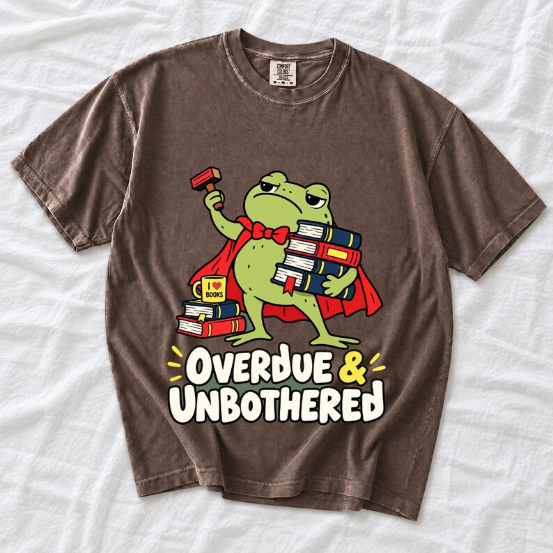 Grumpy cartoon frog librarian holding a stamp and a stack of books with the text Overdue & Unbothered