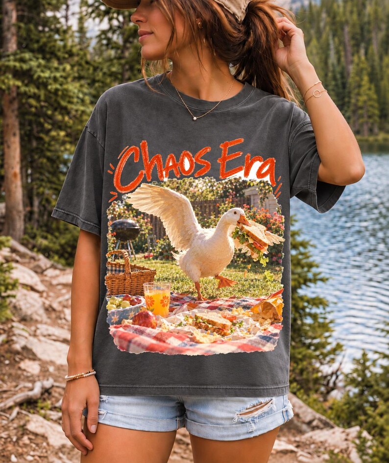 Goose stealing a sandwich from a picnic blanket, 90s film photo style, text "Chaos Era"