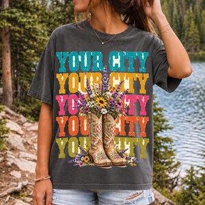 Tan cowboy boots with lavender and wildflowers over a five-line stacked personalized city word in retro colors