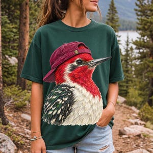Colored-pencil red-headed woodpecker in side profile wearing a backwards corduroy cap, funny birder t-shirt graphic