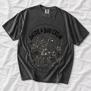 Skeleton bride popping champagne with cheering skeleton bridesmaids and the text Bride & Boo Crew