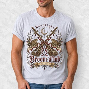 Vintage poster style crossed broomsticks with ribbons, lace and toads, text Moonlight Broom Club Est. 1692