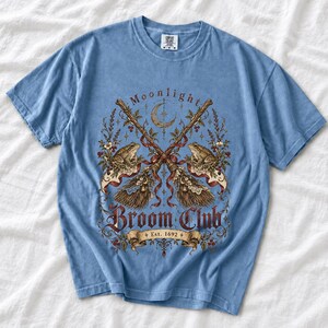 Vintage poster style crossed broomsticks with ribbons, lace and toads, text Moonlight Broom Club Est. 1692
