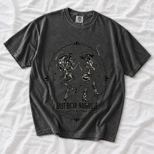 Two cowgirl skeletons in hats line dancing in a starry frame with the text Last Rodeo Nashville
