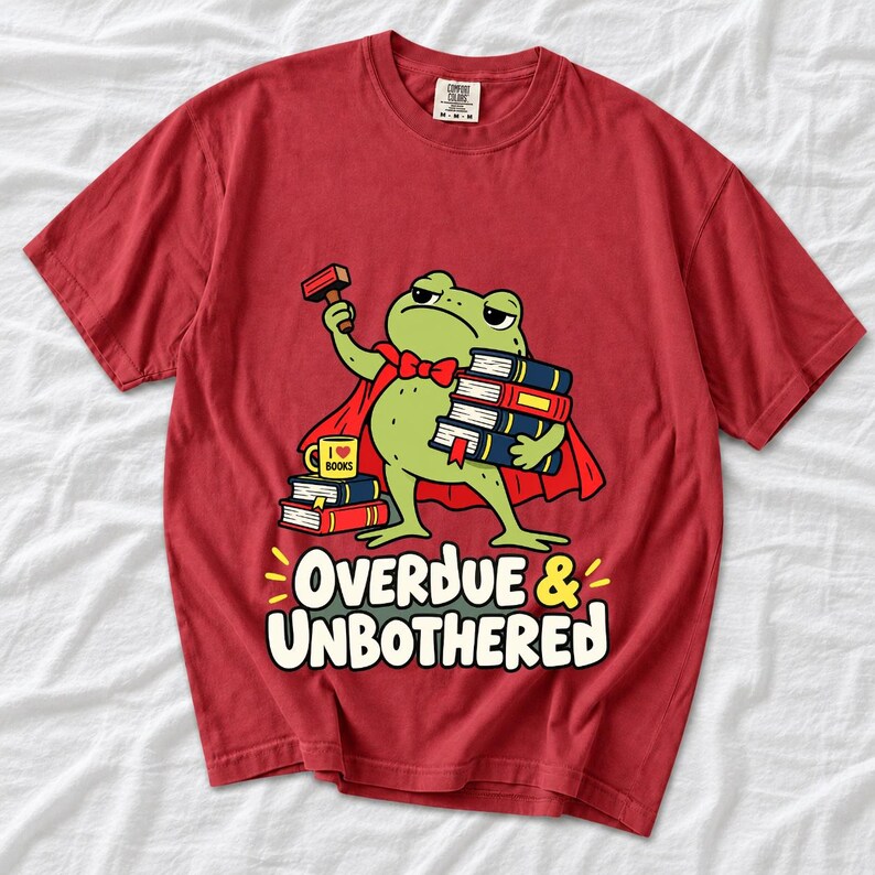 Grumpy cartoon frog librarian holding a stamp and a stack of books with the text Overdue & Unbothered