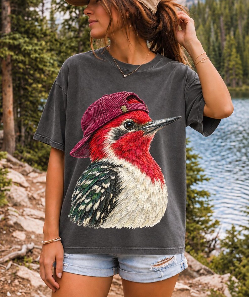 Colored-pencil red-headed woodpecker in side profile wearing a backwards corduroy cap, funny birder t-shirt graphic