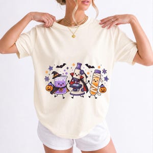 Kawaii beaker, microscope and test tube with faces in Halloween costumes, pastel purple and orange
