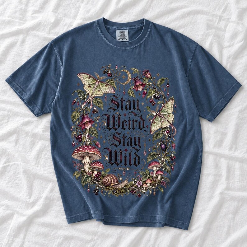 Victorian-style wreath of nightshade, luna moths and toadstools around the words "Stay Weird, Stay Wild"