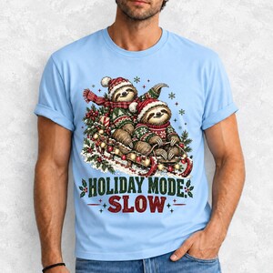 Two sloths in ugly sweaters riding a sled with lights and the text Holiday Mode: Slow