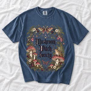 Blackletter text "Mushroom Witch Society" framed by fly agaric mushrooms, ferns and a toad on a mushroom cap