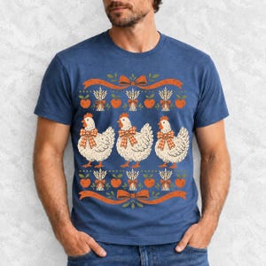 Three fluffy hens with gingham bows between apple and wheat borders, retro folk art fall t-shirt design