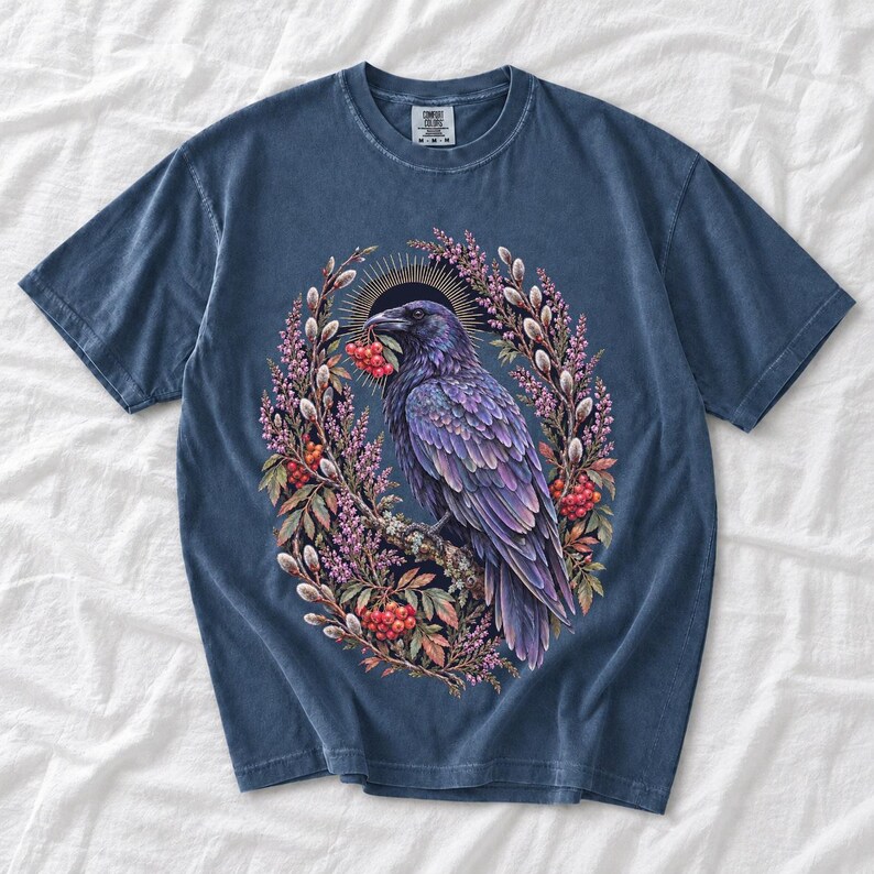 Raven holding a rowan berry inside an oval wreath of heather and catkins, painted cottagecore bird illustration