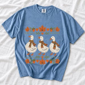 Three white ducks in striped scarves with acorn and maple leaf borders, retro screen print fall t-shirt art