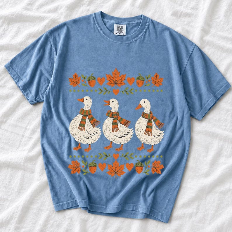 Three white ducks in striped scarves with acorn and maple leaf borders, retro screen print fall t-shirt art