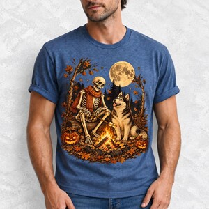 A skeleton in a scarf roasting marshmallows by a campfire beside a husky in an autumn forest under a full moon