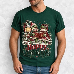 Two frogs singing carols in the snow with a lantern and songbook, text Hoppy Holidays