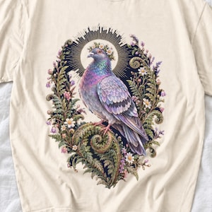 Painted pigeon wearing a daisy crown and glowing halo standing on a fern frond, whimsical cottagecore bird t-shirt art