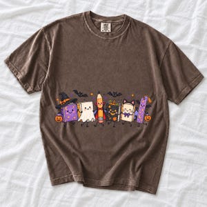 Kawaii books, pencil and bookmark with faces in Halloween costumes, pastel purple and orange