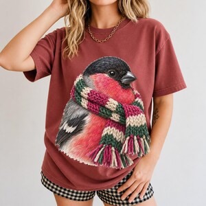 Colored-pencil bullfinch bird wrapped in a chunky striped knit scarf, cozy winter birdwatcher t-shirt art