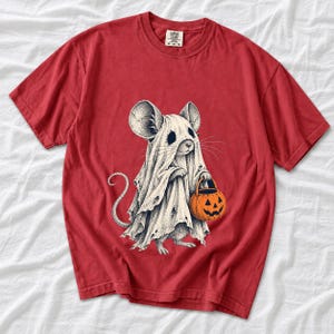 Etched pen illustration of a small mouse in a sheet ghost costume holding a candy bucket, bone white with orange accent