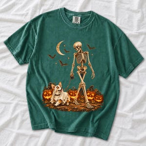 A skeleton walking a corgi in a ghost costume past carved pumpkins under a crescent moon