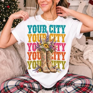 Tan cowboy boots with lavender and wildflowers over a five-line stacked personalized city word in retro colors