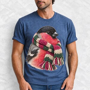 Colored-pencil bullfinch bird wrapped in a chunky striped knit scarf, cozy winter birdwatcher t-shirt art