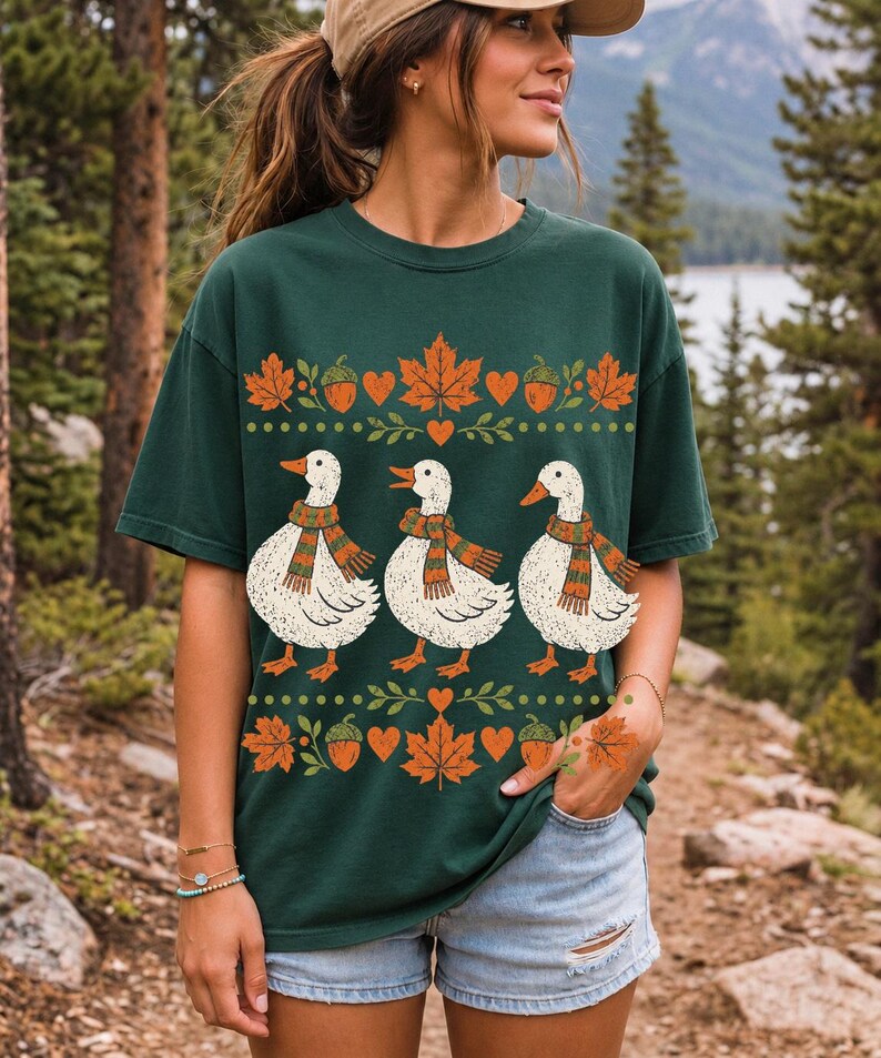 Three white ducks in striped scarves with acorn and maple leaf borders, retro screen print fall t-shirt art