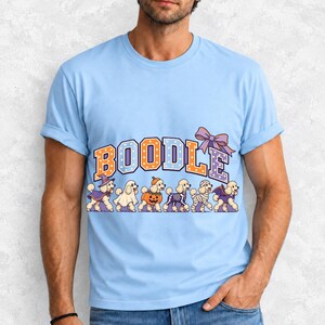 Six poodles in Halloween costumes walking under the arched word BOODLE, lavender and orange polka-dot varsity style