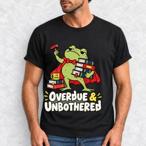 Grumpy cartoon frog librarian holding a stamp and a stack of books with the text Overdue & Unbothered
