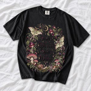Victorian-style wreath of nightshade, luna moths and toadstools around the words "Stay Weird, Stay Wild"