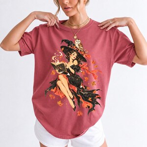 Retro 1950s pin-up witch floating while reading a spell book with an owl on her hat, autumn leaves
