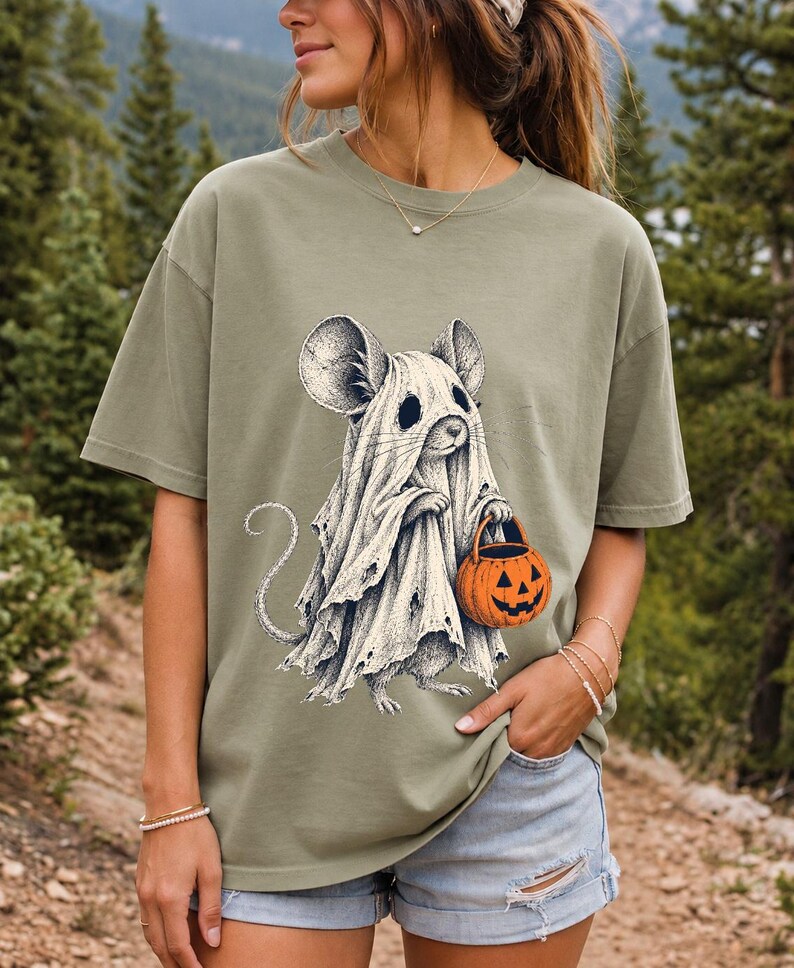 Etched pen illustration of a small mouse in a sheet ghost costume holding a candy bucket, bone white with orange accent