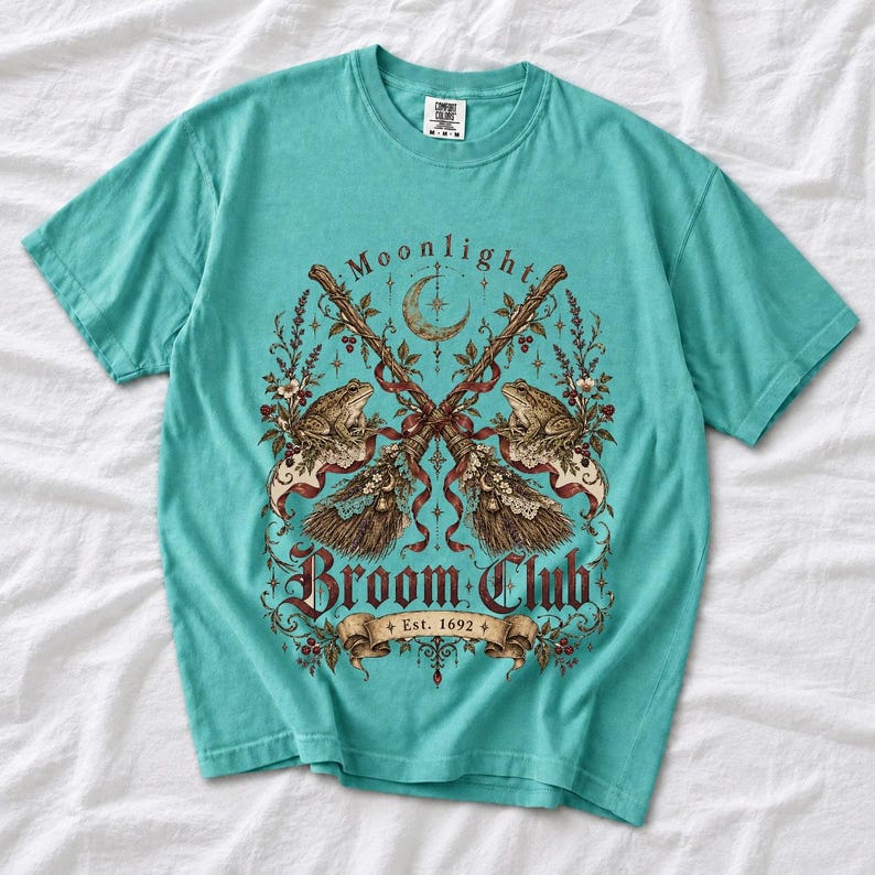 Vintage poster style crossed broomsticks with ribbons, lace and toads, text Moonlight Broom Club Est. 1692