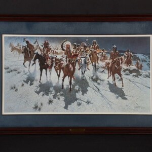 May include: A framed print of a painting depicting a group of Native American men on horseback riding through a snowy landscape. The men are wearing traditional clothing and headdresses, and they are carrying weapons. The painting is set against a backdrop of a dark sky and a distant mountain range.