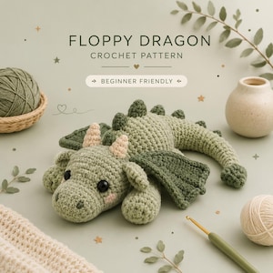 Puede incluir: Un juguete de dragón tejido a ganchillo en hilo verde claro y oscuro con pequeños cuernos color crema y ojos de seguridad negros. El texto FLOPPY DRAGON CROCHET PATTERN BEGINNER FRIENDLY aparece sobre el juguete, junto a ovillos y un ganchillo.