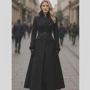 Può includere: Un cappotto lungo e nero, aderente, con collo alto, maniche lunghe e una cintura nera abbinata con fibbia in vita. Il cappotto presenta un corpetto strutturato, dettagli con bottoni e una gonna lunga che si allarga leggermente verso il fondo.