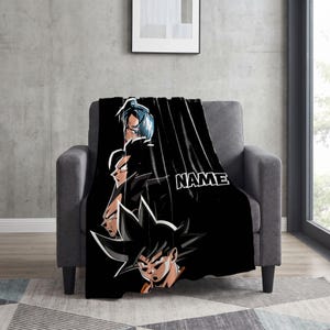 May include: A black throw blanket featuring a vertical graphic of four anime characters from Dragon Ball Z stacked in profile, with the word NAME printed in white capital letters on the right side of the design against the dark background.