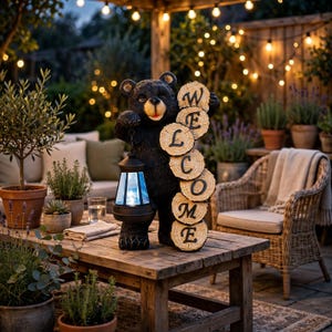 May include: A black bear statue holding a dark lantern in one paw and a vertical stack of five circular wood slices in the other. Each wood slice features a single black letter, spelling out the word WELCOME from top to bottom.