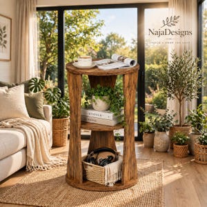 May include: A round, three-tiered wooden side table with a dark brown wood grain finish. The top surface holds a white ceramic mug and an open book. The middle shelf displays a potted green plant and two stacked books. A woven basket sits on the base.