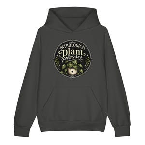 May include: A dark charcoal gray hooded sweatshirt featuring a circular graphic on the chest. The design includes the text "PATHOLOGICAL plant pleaser" in white and cream, surrounding an illustration of a potted plant with a small heart icon.