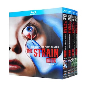 Könnte beinhalten: Ein Blu-ray-Boxset der Serie The Strain, bestehend aus vier Staffeln. Das Cover zeigt eine Nahaufnahme eines menschlichen Auges mit einem wurmartigen Parasiten, gehalten von einer blau behandschuhten Hand. Der Text lautet The Strain, The Complete First Season.