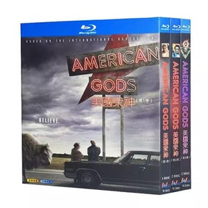 Peut inclure: Un coffret Blu-ray de la série American Gods présentant un ciel sombre et nuageux, une grande enseigne néon, un bison, une voiture noire et deux silhouettes. La couverture affiche le texte American Gods, Believe et des caractères chinois.