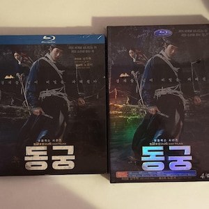 Peut inclure: Deux boîtiers rectangulaires Blu-ray et DVD présentant une affiche de film sombre et atmosphérique avec une personne en tenue traditionnelle tenant un arc. Le texte coréen "동궁" est affiché en gros caractères gras en bas.