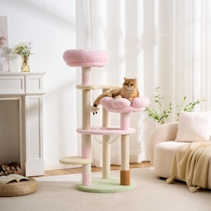 Pode incluir: Uma árvore para gatos de vários níveis com uma base circular verde-clara, postes envoltos em sisal bege com detalhes em rosa, um poleiro circular rosa, uma plataforma rosa em forma de flor e uma tigela de acrílico transparente com um gato castanho.