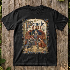 May include: A black short-sleeved t-shirt featuring a central graphic of two knights in armour dueling with swords inside an ornate, medieval-style archway. Above the knights, a figure watches from a balcony. The text reads, the female gaze.