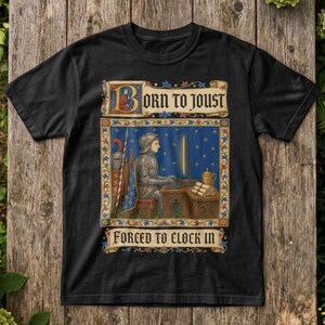 Könnte beinhalten: Ein schwarzes T-Shirt mit einer mittelalterlichen Grafik eines Ritters in voller Rüstung, der an einem Schreibtisch sitzt und einen Computer benutzt. Der Text lautet BORN TO JOUST und FORCED TO CLOCK IN. Das Design ist von einem verzierten Rand umgeben.