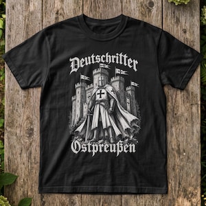 Könnte beinhalten: Ein schwarzes Kurzarm-T-Shirt mit einem weißen Grafikdruck eines mittelalterlichen Ritters in Rüstung vor einer steinernen Burg. Der Text "Deutschritter" ist bogenförmig darüber angeordnet und "Ostpreußen" steht unter der Illustration.