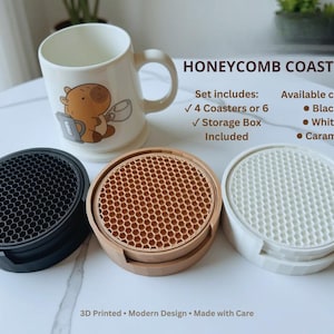 Pode incluir: Um conjunto de porta-copos em favo de mel com uma caneca branca com um personagem. O conjunto inclui porta-copos circulares pretos, cor de caramelo e brancos com padrão hexagonal, cada um numa caixa. Texto para 4 ou 6 porta-copos incluído.